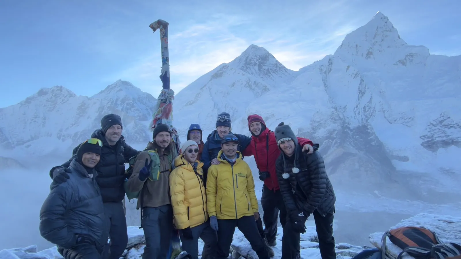 The group at sunrise on top of Kala Patthar with Mount Everest behind them